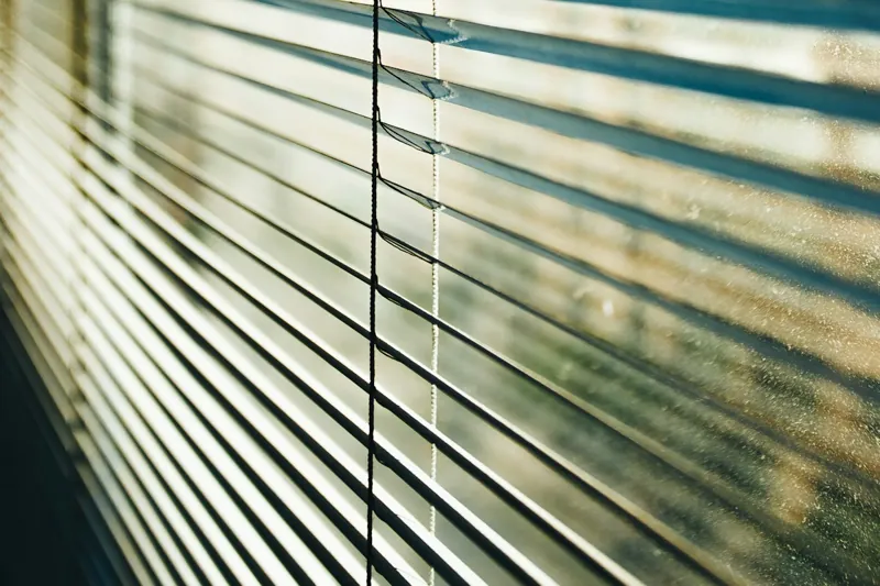White horizontal window blinds filtering daylight